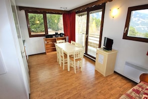 A cozy room with a wooden dining table, chairs, a small TV on a cabinet, and a heater.