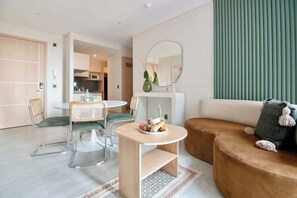 A modern living room with a round table, two chairs, a sofa, and a large mirror.