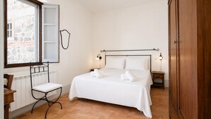Une chambre à coucher comprenant un lit, des tables de chevet, une chaise, une fenêtre et une armoire.