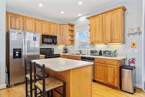 A modern kitchen with wooden cabinets, stainless steel appliances, and a central island.