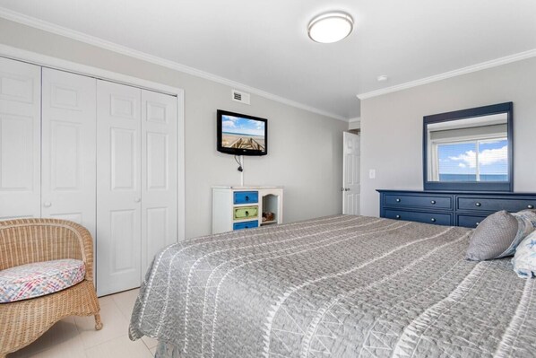 A bedroom with a bed, a television, a dresser, and a chair.