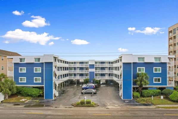 Un hôtel à plusieurs étages doté d’une cour intérieure, d’un parking et offrant une vue sur un ciel dégagé.