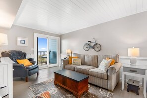 A living room with a sofa, armchairs, a coffee table, and a bicycle mounted on the wall.
