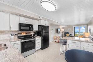 A modern kitchen with stainless steel appliances, white cabinetry, and a large island with bar stools.