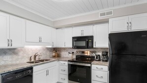 Una cocina moderna con armarios blancos, un refrigerador negro, un microondas, una estufa y un lavavajillas.