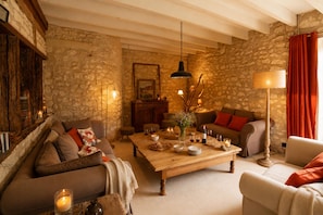 A cozy living room with stone walls, a wooden coffee table, and a fireplace.