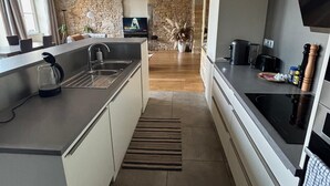 A modern kitchen with a stone wall, a large island, and a TV mounted on the wall. - The panorama (Lyon)