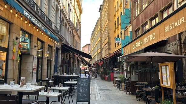 A street lined with restaurants and cafes, outdoor seating, and a clear sky. - The panorama (Lyon)