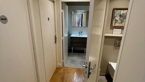 A hallway with wooden flooring, a mirror, a sink, and a framed picture on the wall. - The panorama (Lyon)