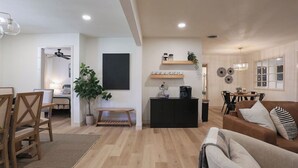 Un salon moderne avec une table à manger en bois, un canapé et un meuble noir.