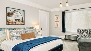 Une chambre à coucher comprenant un lit, une table de chevet, une lampe et une œuvre d’art.