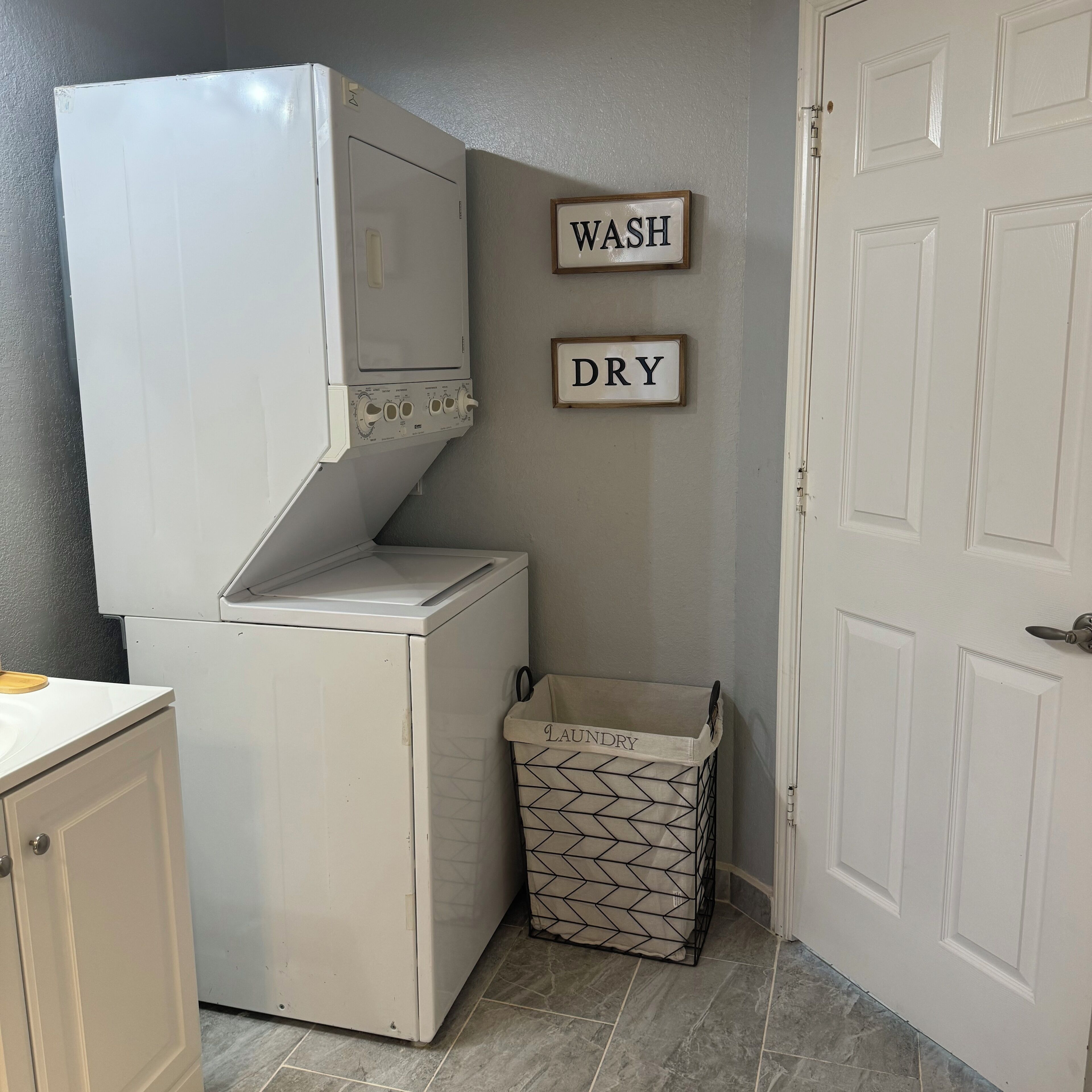 A compact laundry area with a washing machine, a drying machine, and a laundry basket.