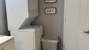 A compact laundry area with a washing machine, a drying machine, and a laundry basket.