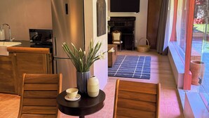 A modern kitchen with a stainless steel refrigerator, a dining table with two wooden chairs, and a vase with flowers. - Parque Juan Diego (Zapopan)