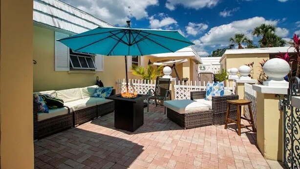 An outdoor patio with a sofa, a table, and an umbrella. - Sunsets over Siesta Key in this cozy 2+2 condo
 (Sarasota)