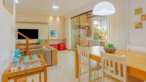 Una sala de estar moderna con televisor, sofá y comedor.