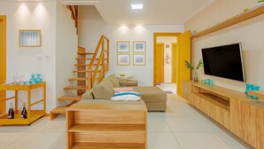 Una sala de estar moderna con un sofá de madera, un televisor y una escalera.