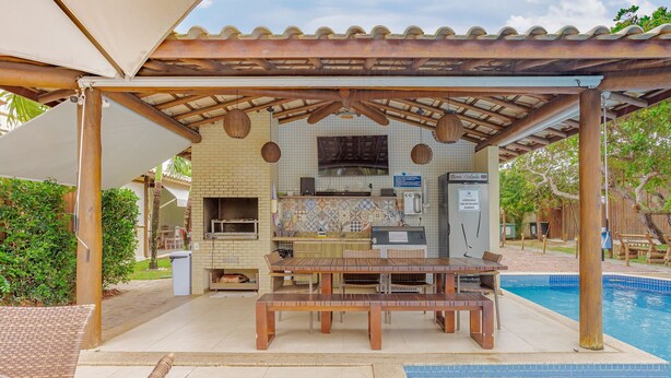 Un área de cocina al aire libre con piscina y mobiliario de patio.