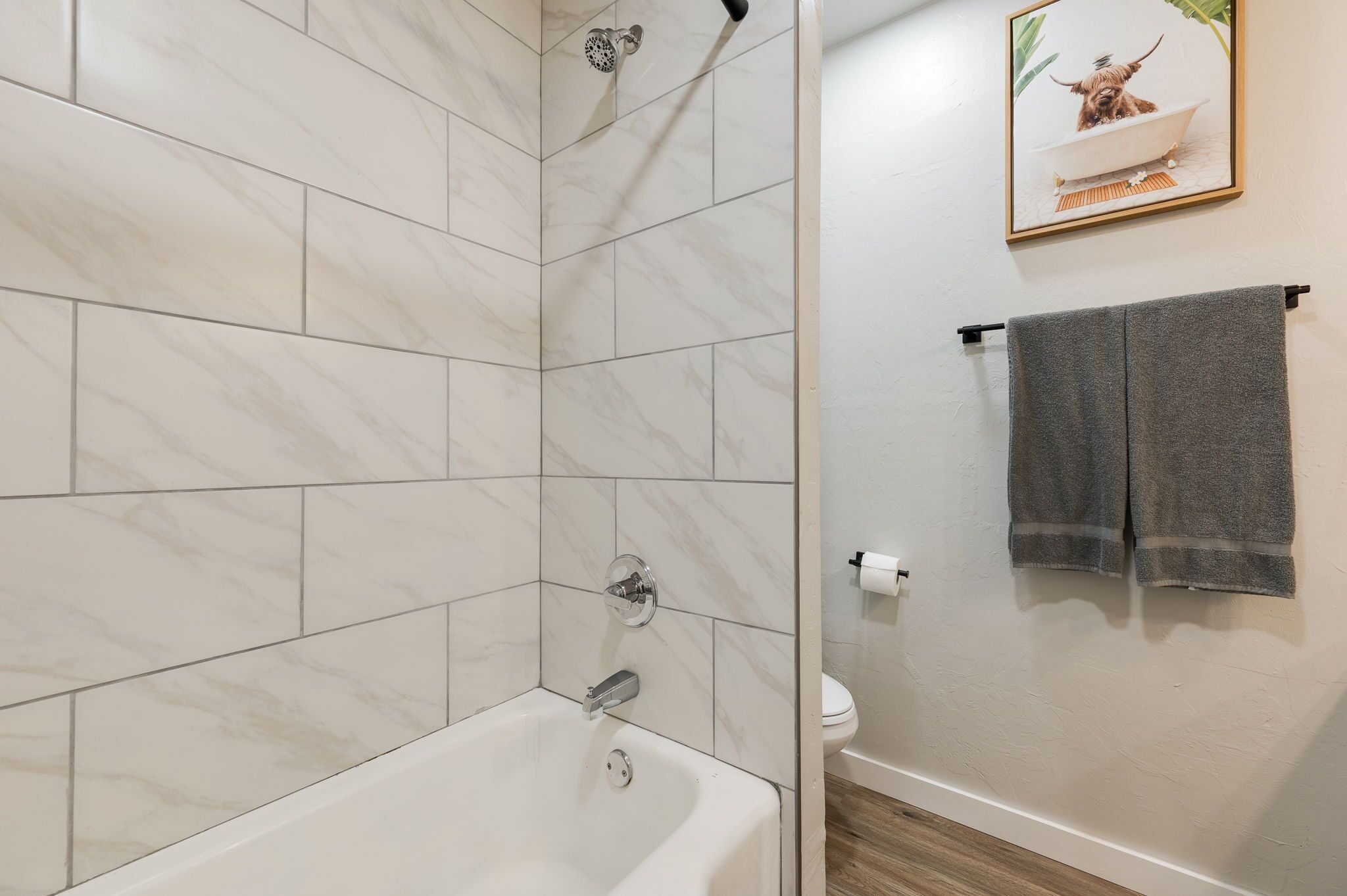 A bathroom with a bathtub, a showerhead, and a toilet.