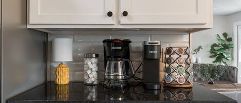 A kitchen with white cabinets, a coffee maker, a glass carafe, and a decorative tray.