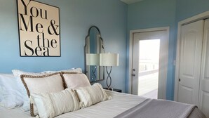 Un dormitorio con cama, almohadas, una lámpara de noche, un espejo y una puerta.