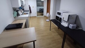 A modern kitchen with a microwave, coffee maker, and a fan. There is a dining area in the background with a table and chairs. - Ocean's Guesthouse - foreigners only (Seoul)