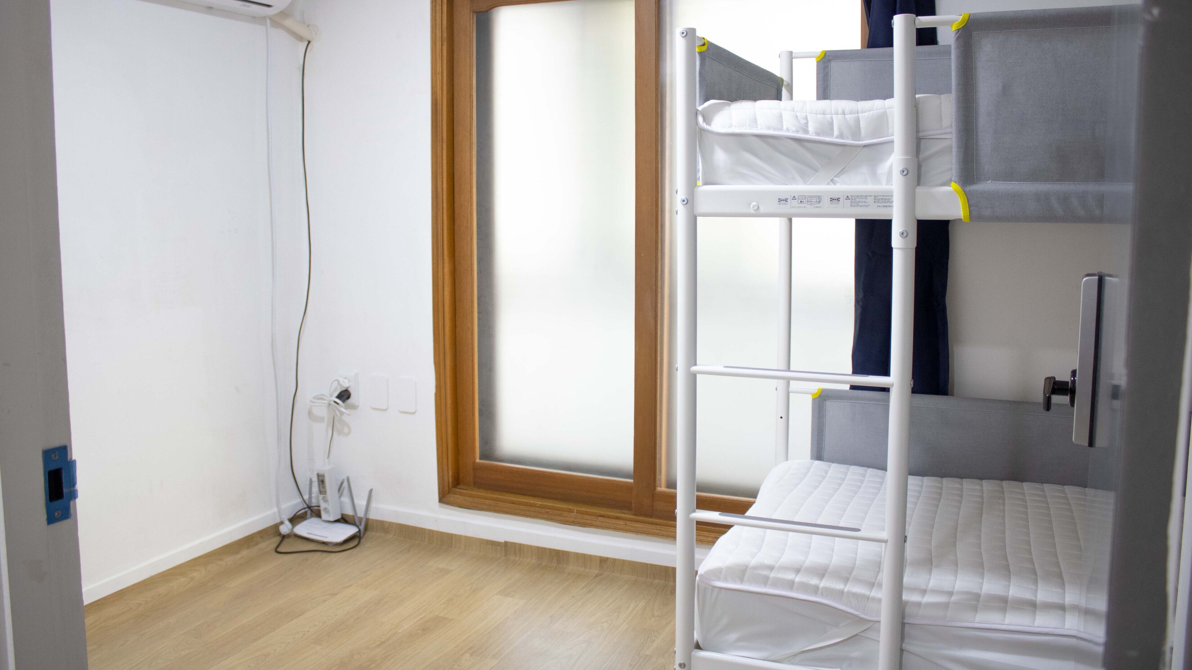 A bunk bed room with a window, a power outlet, and a heater.
