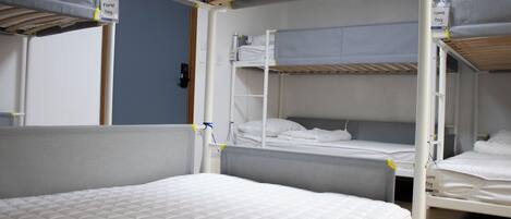 A bunk bed room with a bunk bed on the left and a single bed on the right. There are name tags on the beds.