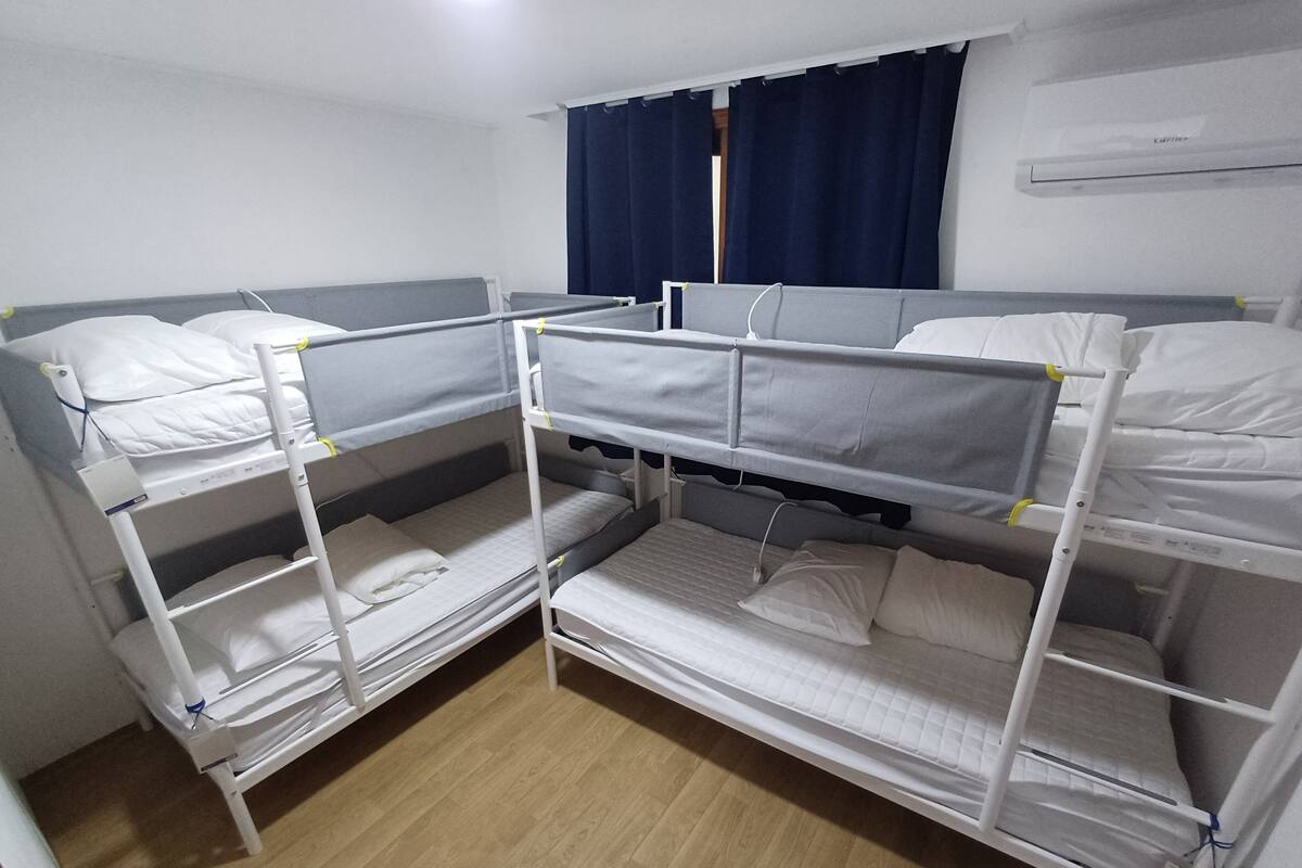 A bunk bed room with white bedding and a wooden floor.