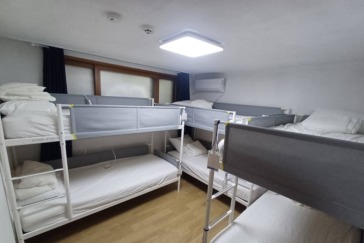 A bunk room with three bunk beds, a bedside table, and a wall-mounted air conditioning unit.