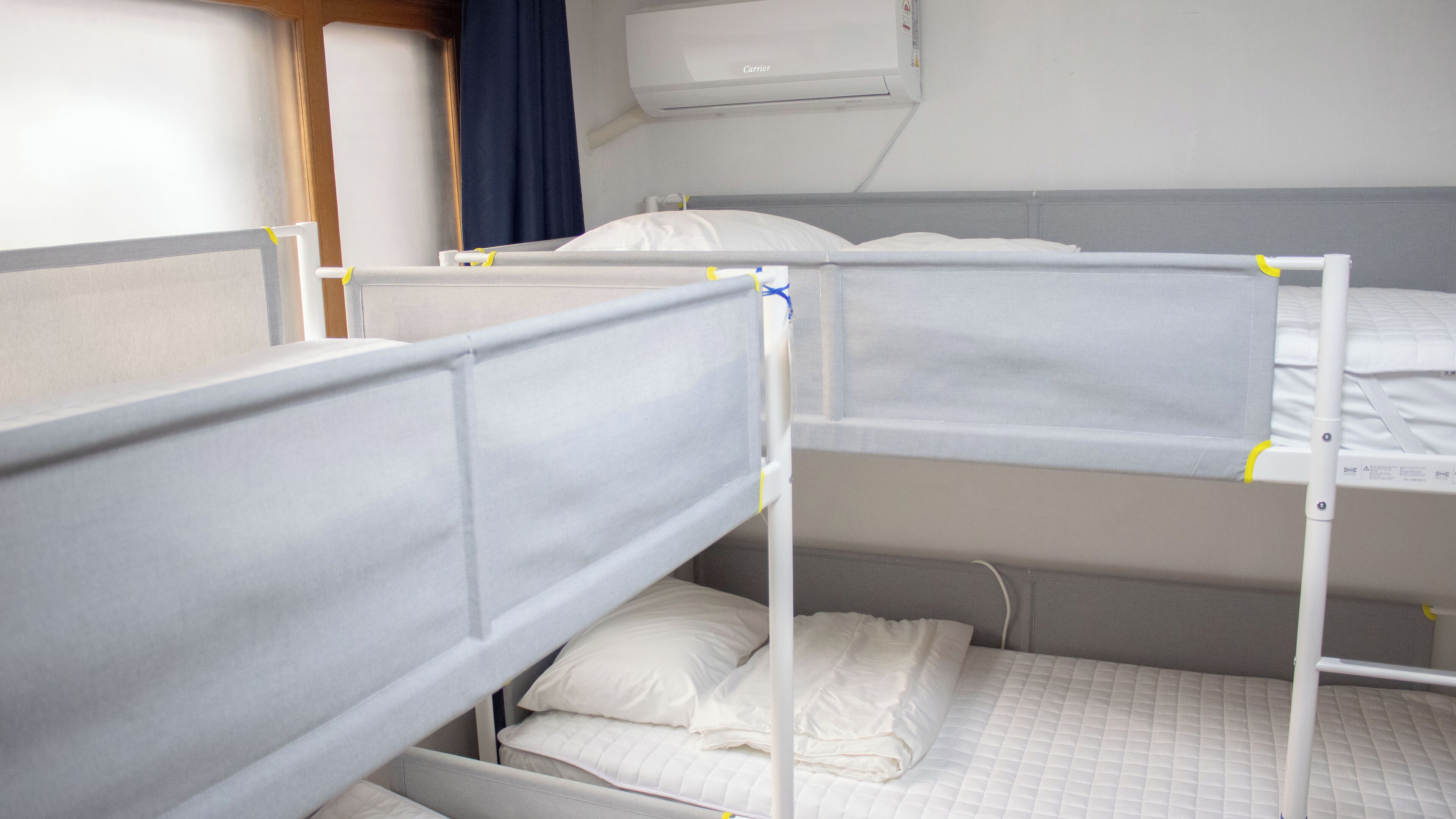 Ein Schlafzimmer mit Etagenbetten, einem Fenster, einem Vorhang und einer Klimaanlage.