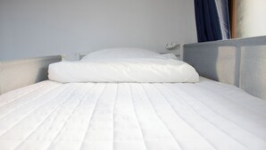 A neatly made bed with a white mattress and pillow, grey headboard, and a white bedside table with a lamp. - Ocean's Guesthouse - foreigners only (Seoul)