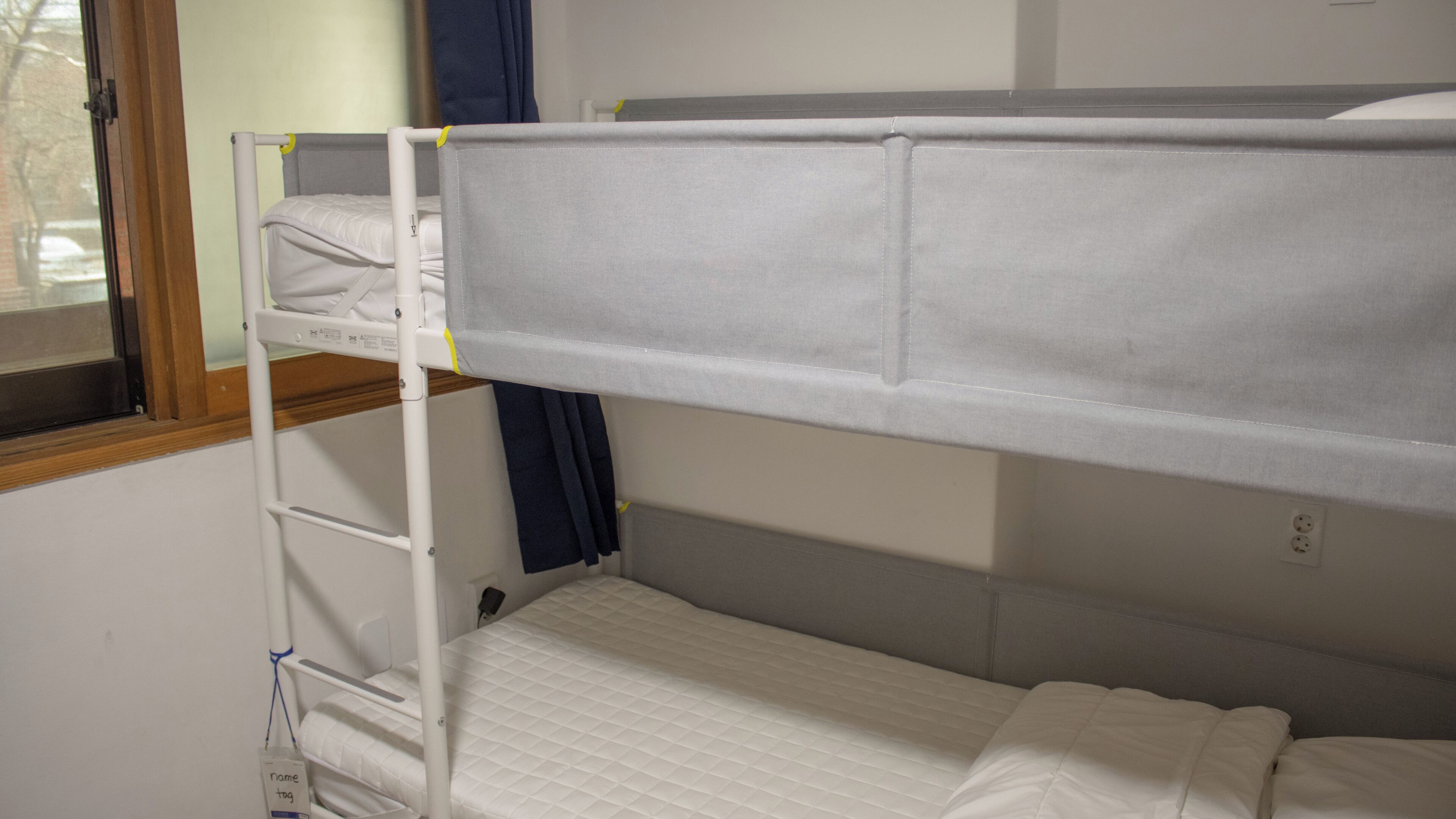 Ein Etagenbett mit weißer Matratze und einem unterem Bett mit gesteppter Decke.