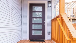 A wooden front porch with a dark-colored front door and a small window above it.