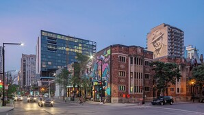 A city street with modern buildings, a mural on a brick building, and a restaurant with outdoor seating. - Luxurious Castle Loft Apartment in Montreal (Montreal)