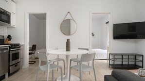 A modern kitchen with white cabinets, a built-in oven, and a dining area with a round table and four chairs. - Luxurious Castle Loft Apartment in Montreal (Montreal)