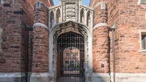 Ein historisches Gebäude mit einem markanten Bogenportal, Steinsäulen und einem Schild über der Tür.
