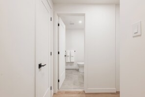 A hallway leading to a bathroom with a toilet and a towel rack. - Modern Studio Haven in Le Mont (Montreal)