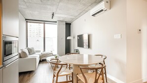 Una sala de estar moderna con una mesa redonda de madera, un sofá blanco y un televisor.
