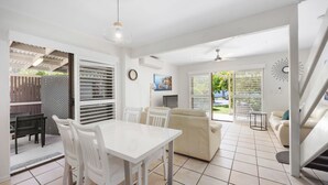A spacious living area with a dining table, chairs, a sofa, and a staircase leading to another level. - Cassindah 7 Noosaville (Noosaville)