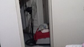 Et værelse med en seng, et rødt tæppe, et mønstret sengetæppe og en døråbning til et andet værelse.