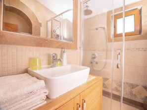 Features a large sink, mirror, and shower area with a glass door.