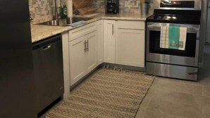 Una cocina moderna con gabinetes blancos, un refrigerador de acero inoxidable, un microondas y un horno.