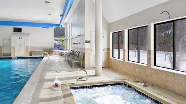 An indoor swimming pool with a hot tub, seating area, and large windows. - Condo With Mountain and Lake Views/Clubhouse Access (Keystone)