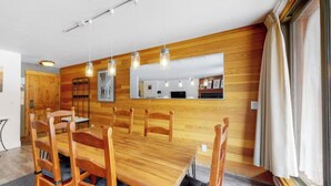 A dining area with a wooden table and chairs, a large mirror, and hanging pendant lights. - Condo With Mountain and Lake Views/Clubhouse Access (Keystone)
