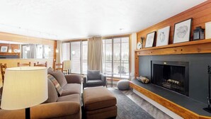 A cozy living room with a fireplace, a sofa, a coffee table, and a dining area with chairs. - Condo With Mountain and Lake Views/Clubhouse Access (Keystone)
