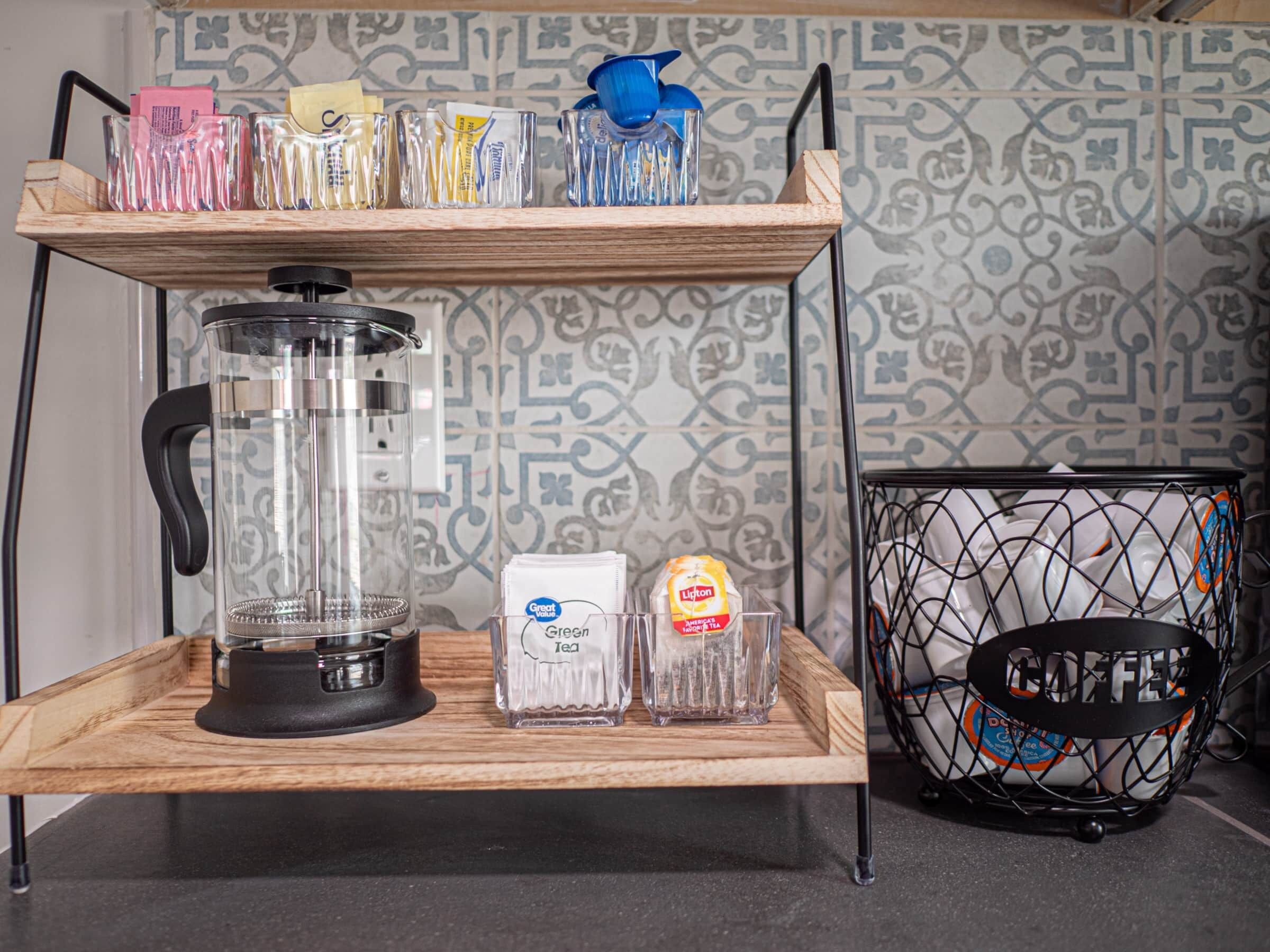 A kitchen counter with a coffee maker, a glass carafe, and a coffee grinder.