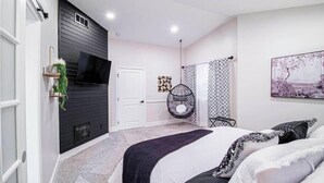 Ein modernes Schlafzimmer mit einem Bett, einem Hängesessel und einem an der Wand befestigten Fernseher.