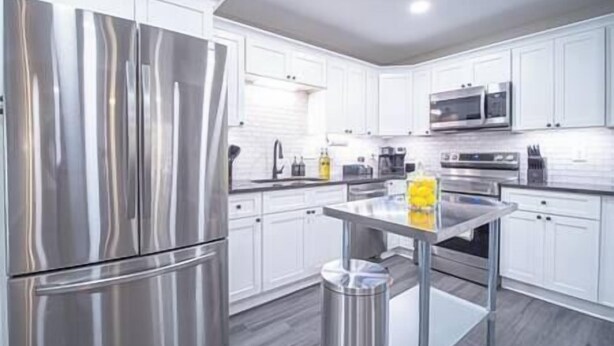 A modern kitchen with stainless steel appliances, white cabinetry, and a central island.
