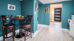 Een keuken met blauwgroene wanden, een houten vloer en een eethoek met twee stoelen en een tafel.